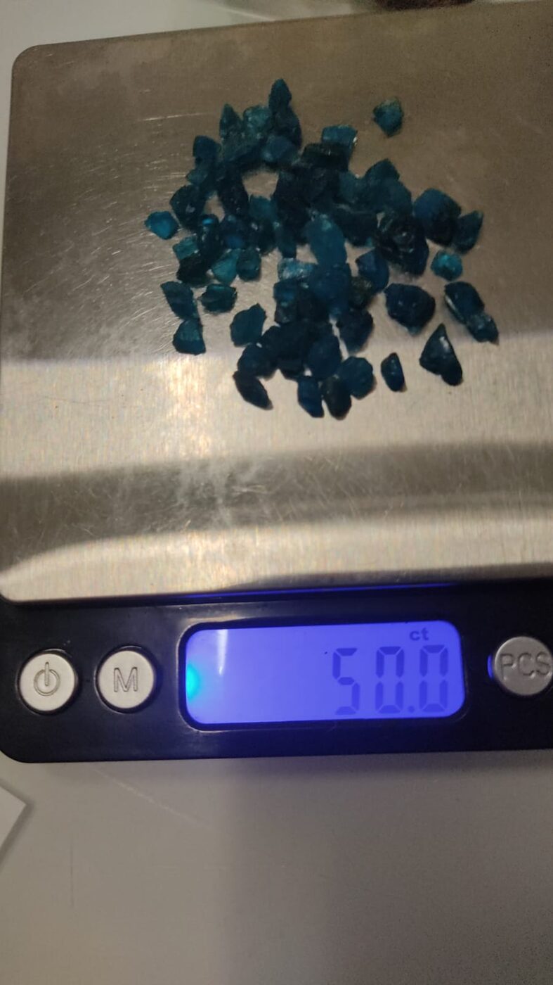 Neonblaue Apatit-Kristalle auf der Waage
